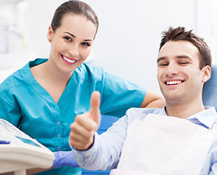 Man in dental chair gives thumbs up
