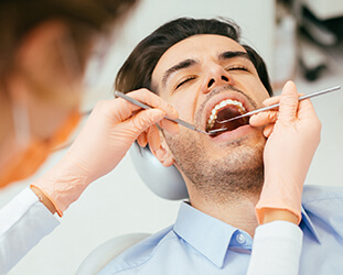 Male patient examined in dental chair with eyes closed