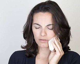 Woman holding cold compress to cheek