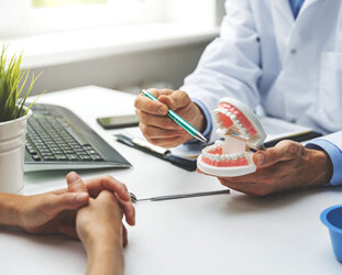 patient pointing to model of teeth with pen