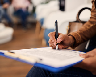 Person filling out paperwork on a clipboard 
