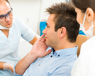 Male patient in dental chair holding cheek