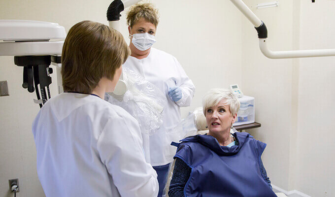 Patient in dental chair talking to team members