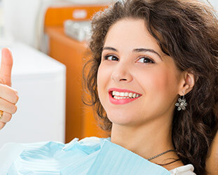 Patient in dental chair giving thumbs up