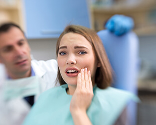 Upset woman holding cheek in dental chair