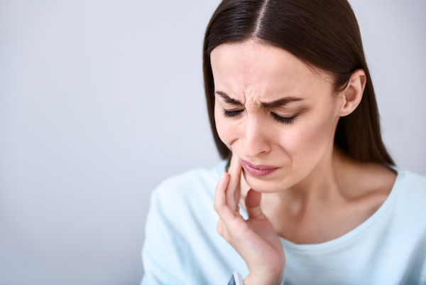 woman with toothache touching cheek