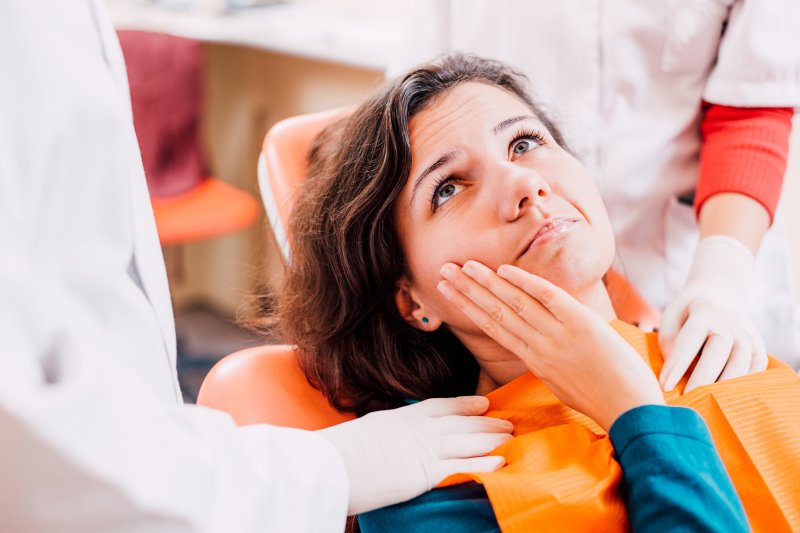 patient holding her tooth and looking at her dentist