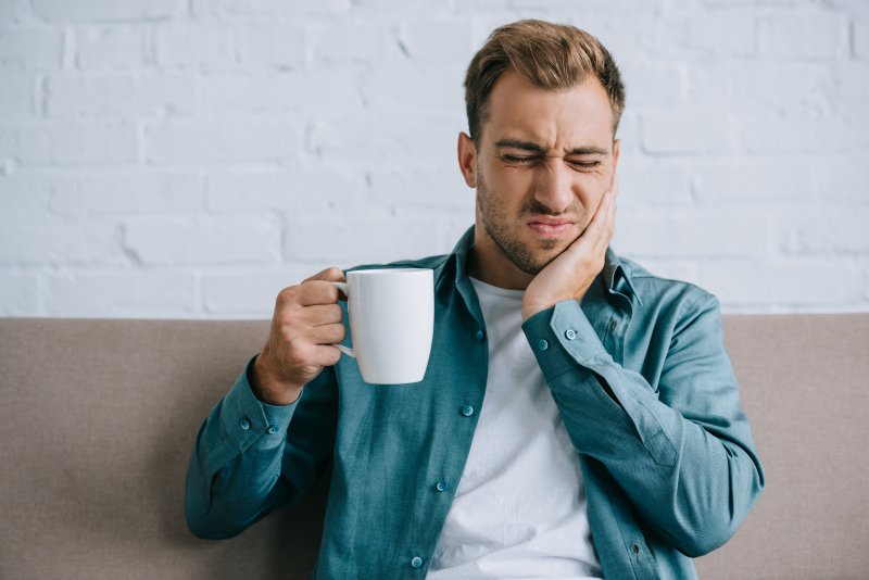 Man holding his cheek in pain because he needs a root canal