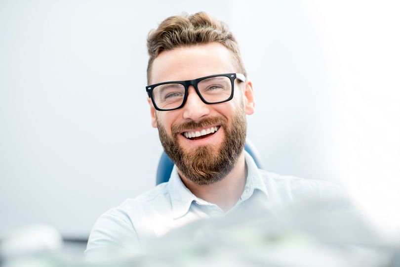 man smiling while sitting in dental chair 